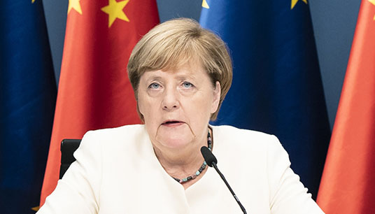 Angela Merkel auf einer Pressekonferenz vor Europaflaggen