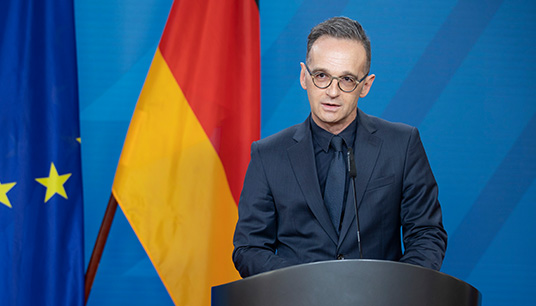 Deutscher Außenminister Heiko Maas vor Flaggen
